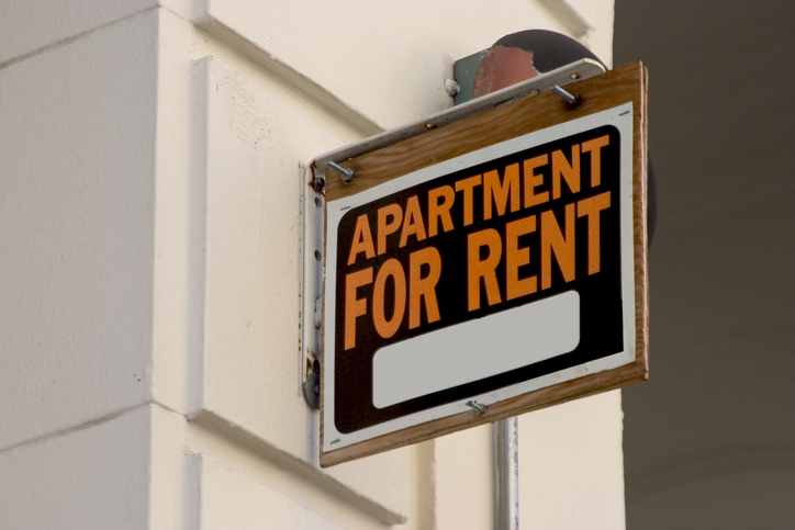 A for rent sign on display on the side of a down town apartment building.
