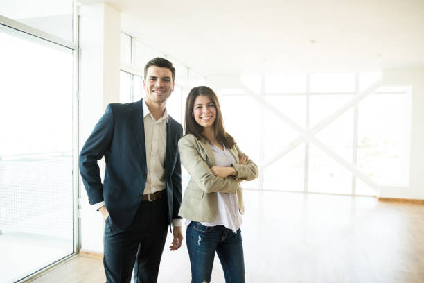 Portrait of smiling male and female real estate agents standing in new apartment