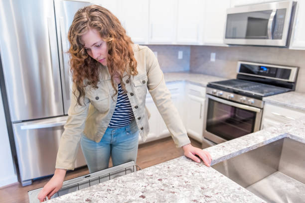 Young woman opening inspecting dishwasher